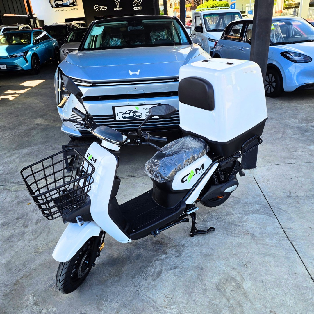 CAM 01-EV 2026 - Blanco - Vista frontal con box trasero. Caja plástica blanca cerrada opcional: US$200 adicionales. Compatible con CAM 01 EV y CAM 02 EV; no incluida en el precio base de la moto.